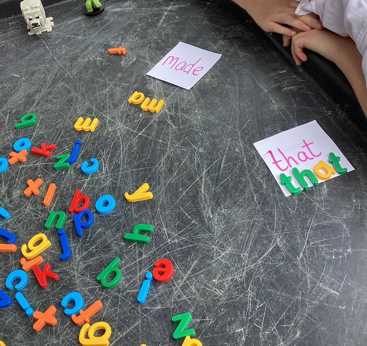 A child arranging colourful letters to match handwritten word cards