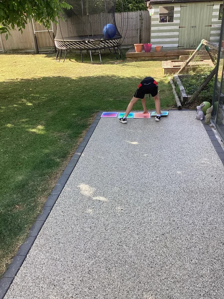 A child stepping across colourful sensory tiles on the garden path