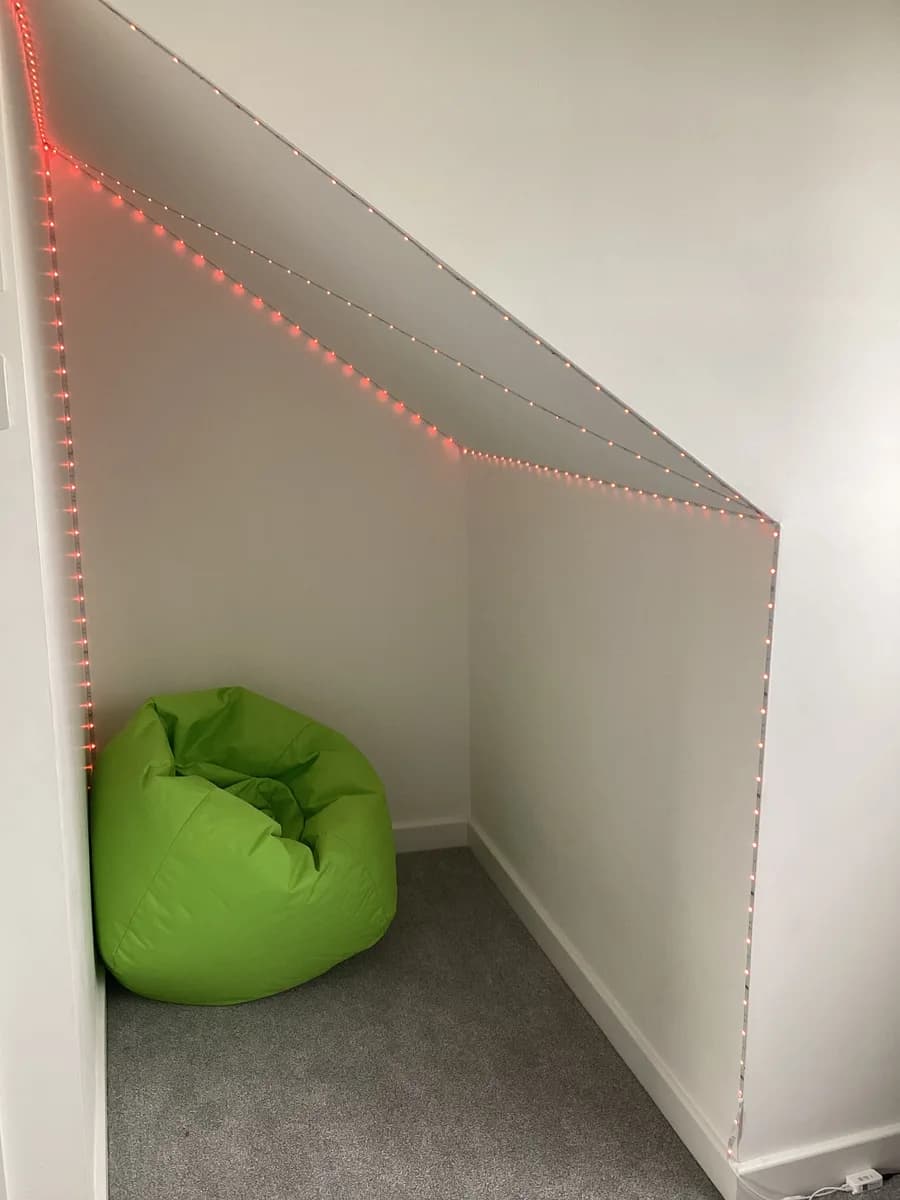 A green beanbag in a small nook edged with string lights